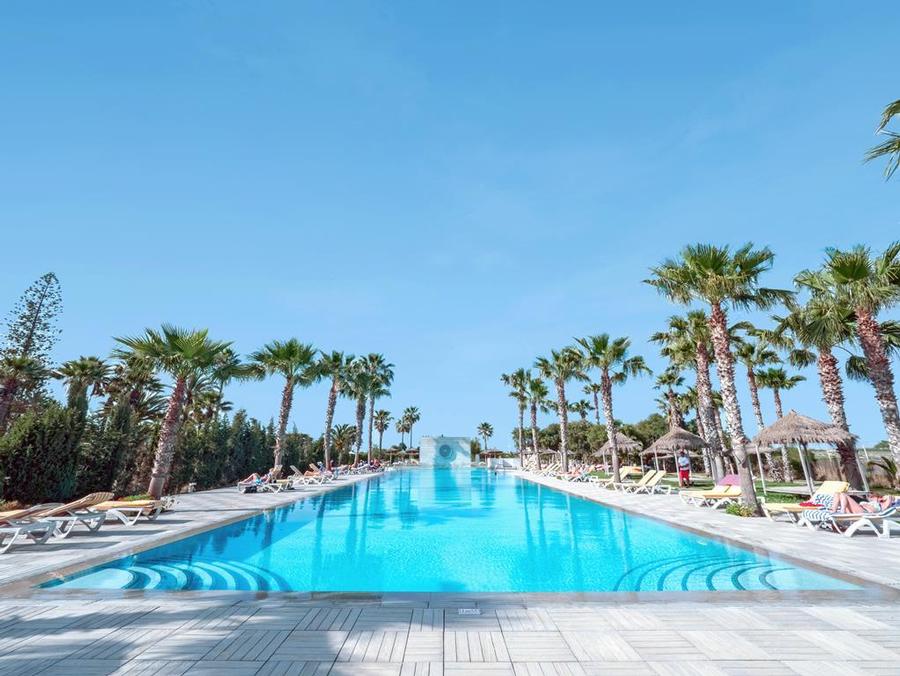 Vue panoramique de la piscine extérieure entourée de chaises longues au Seabel Alhambra Beach